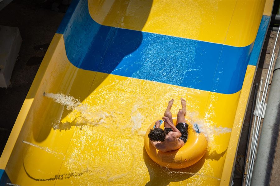 Rider splashing down a yellow and blue waterslide on an inflatable ring